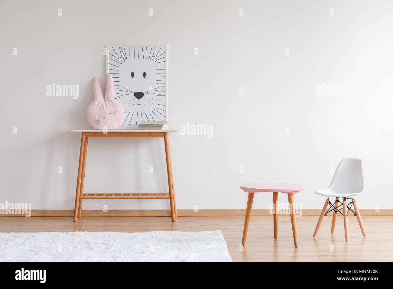 Lion poster et pastel oreiller sur table en bois dans des chambre de l'enfant avec chaise blanche et rug Banque D'Images