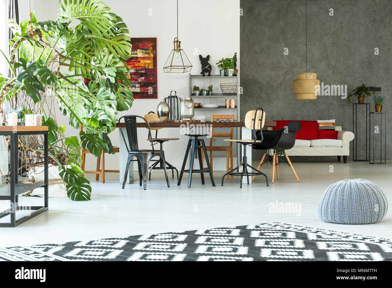 Cet appartement lumineux et moderne avec une table à manger, canapé, pouf et monstera Banque D'Images
