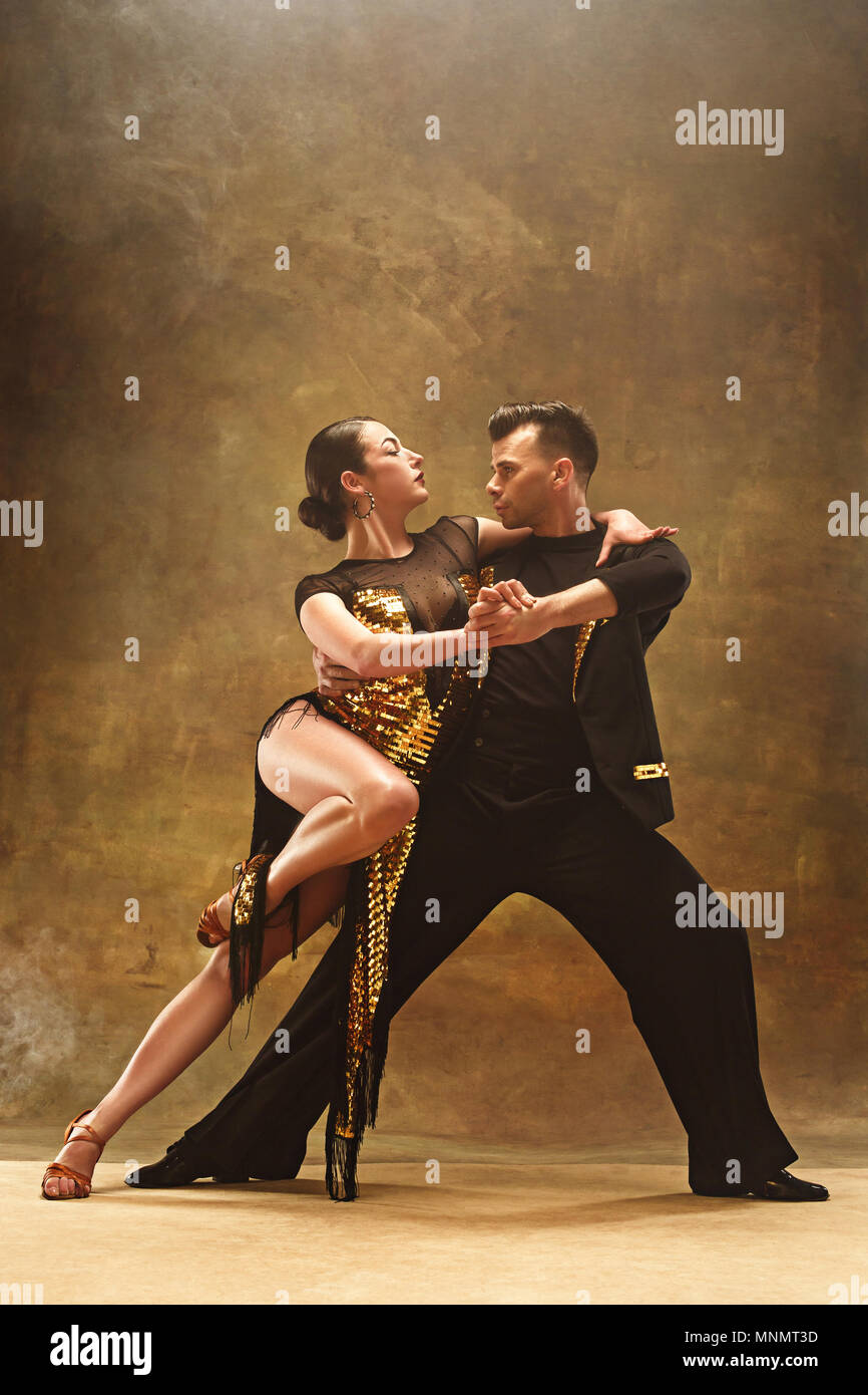 Salle de bal de danse en couple danse robe d'or sur fond de studio. Banque D'Images