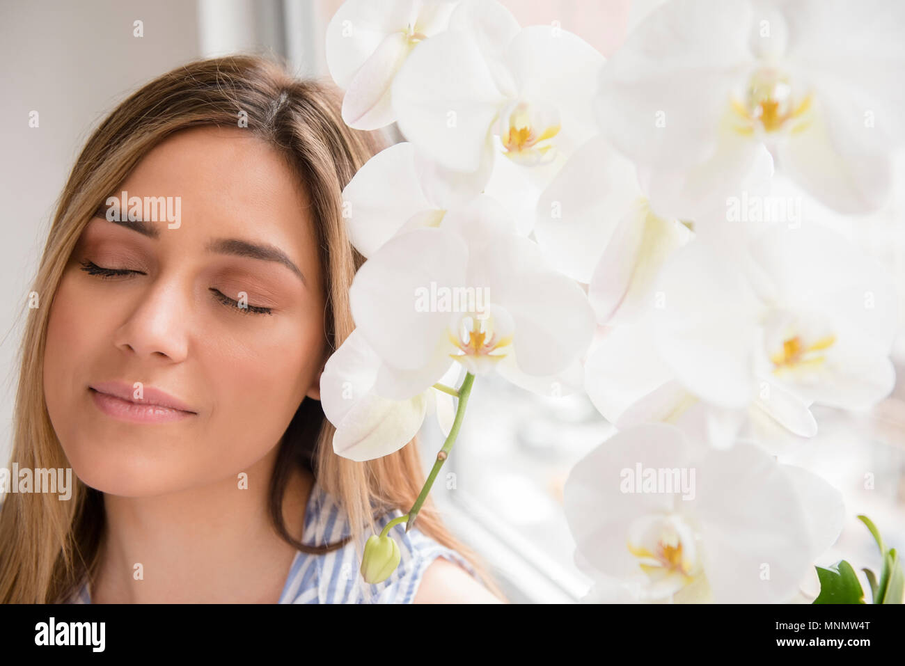Portrait de jeune femme aux yeux clos à côté de fleurs orchidée blanche Banque D'Images Portrait de jeune femme aux yeux clos à côté de fleurs orchidée blanche Banque D'Images