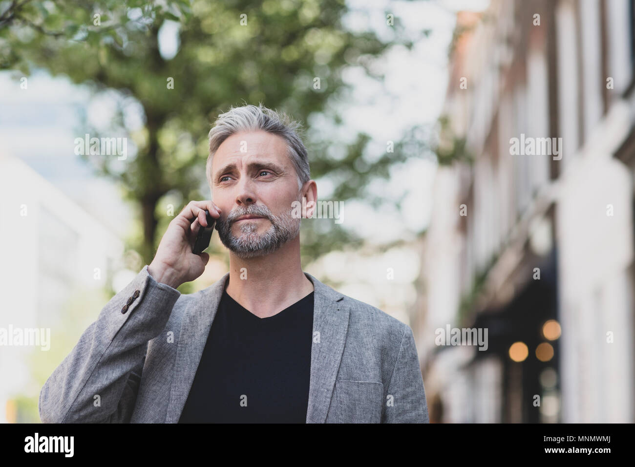 Homme mature et marche sur smartphone en ville Banque D'Images