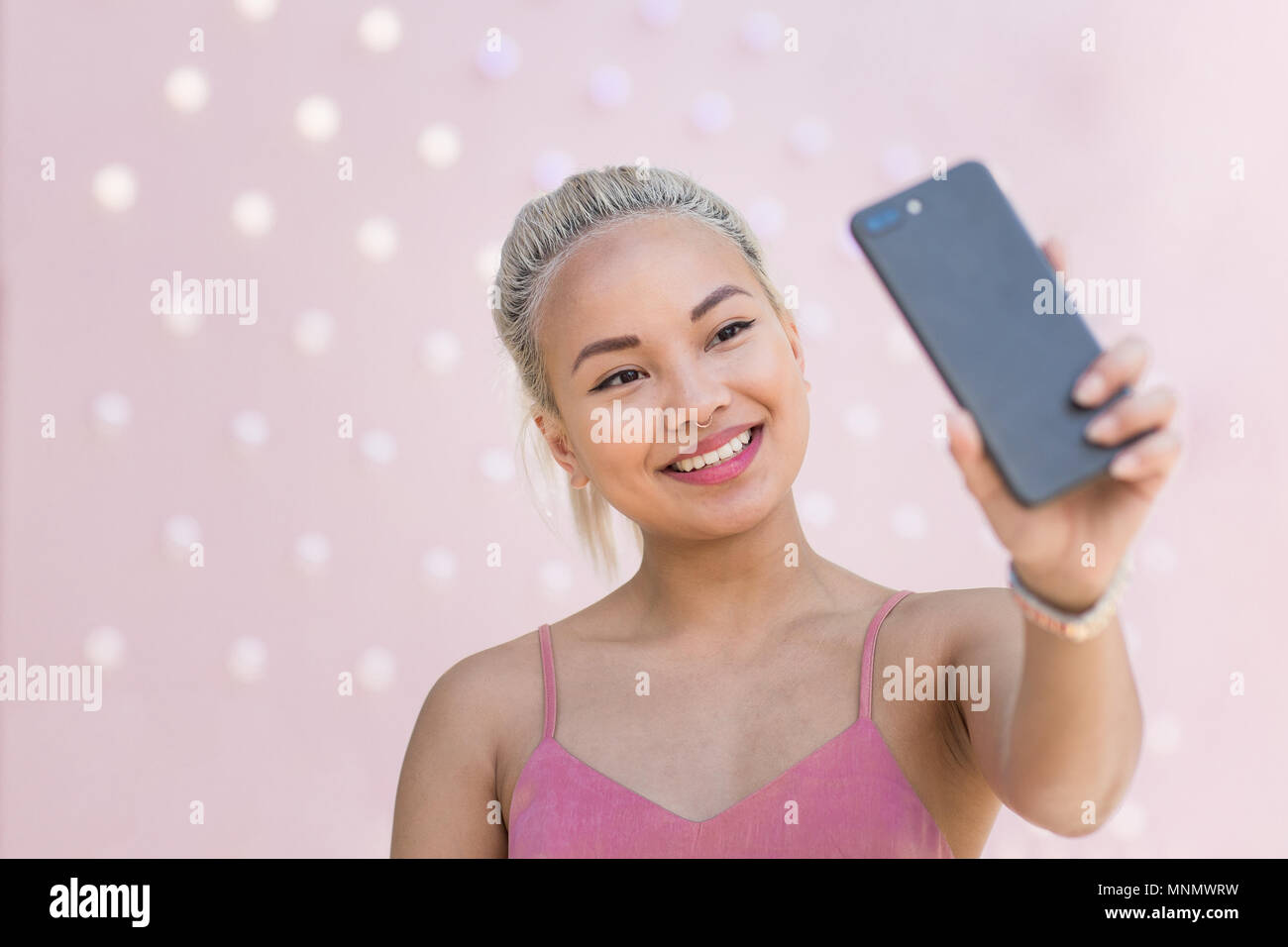 Les jeunes femmes adultes prenant fond rose avec des selfies Banque D'Images