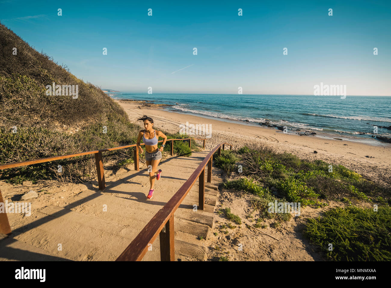 États-unis, Californie, Newport Beach, Woman running up stairs Banque D'Images