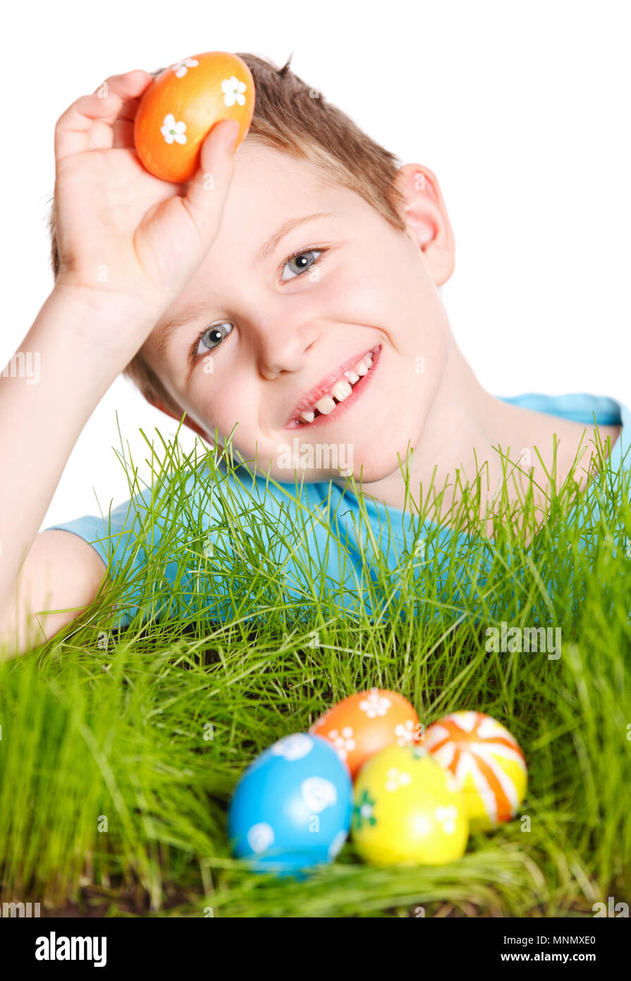 Cute boy à la recherche des oeufs de Pâques cachés dans une herbe Banque D'Images