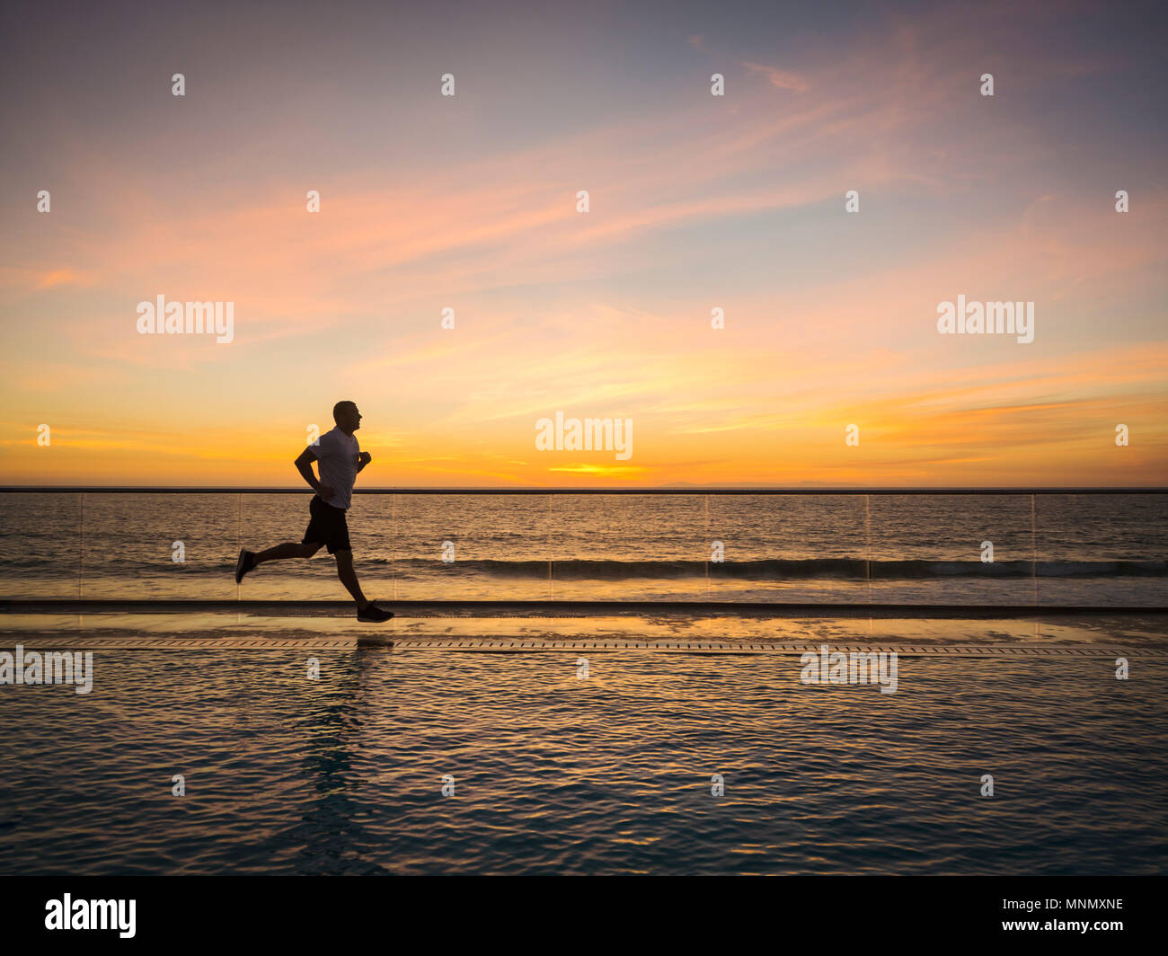 Man jogging le long de la piscine Banque D'Images