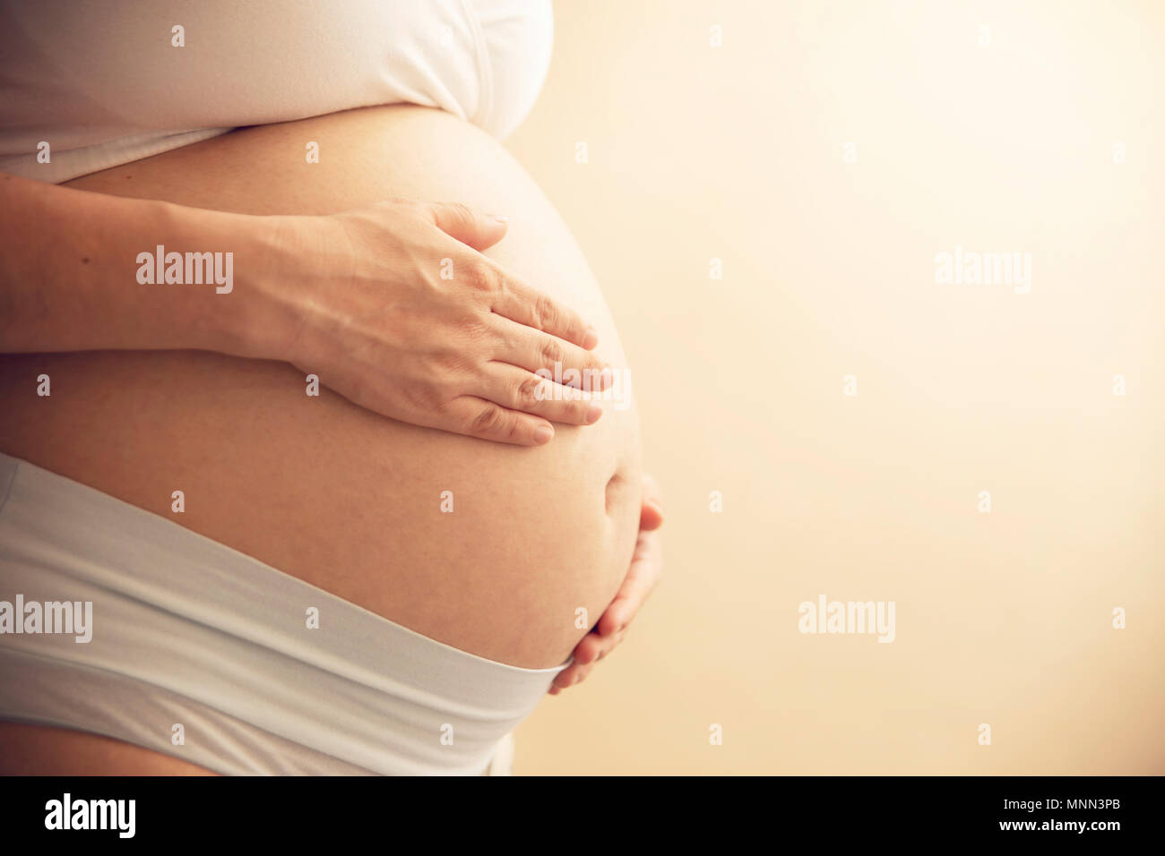 Jeune femme enceinte détient les mains sur son ventre. préparation et d'attente concept. close-up avec copie espace horizontal. Banque D'Images