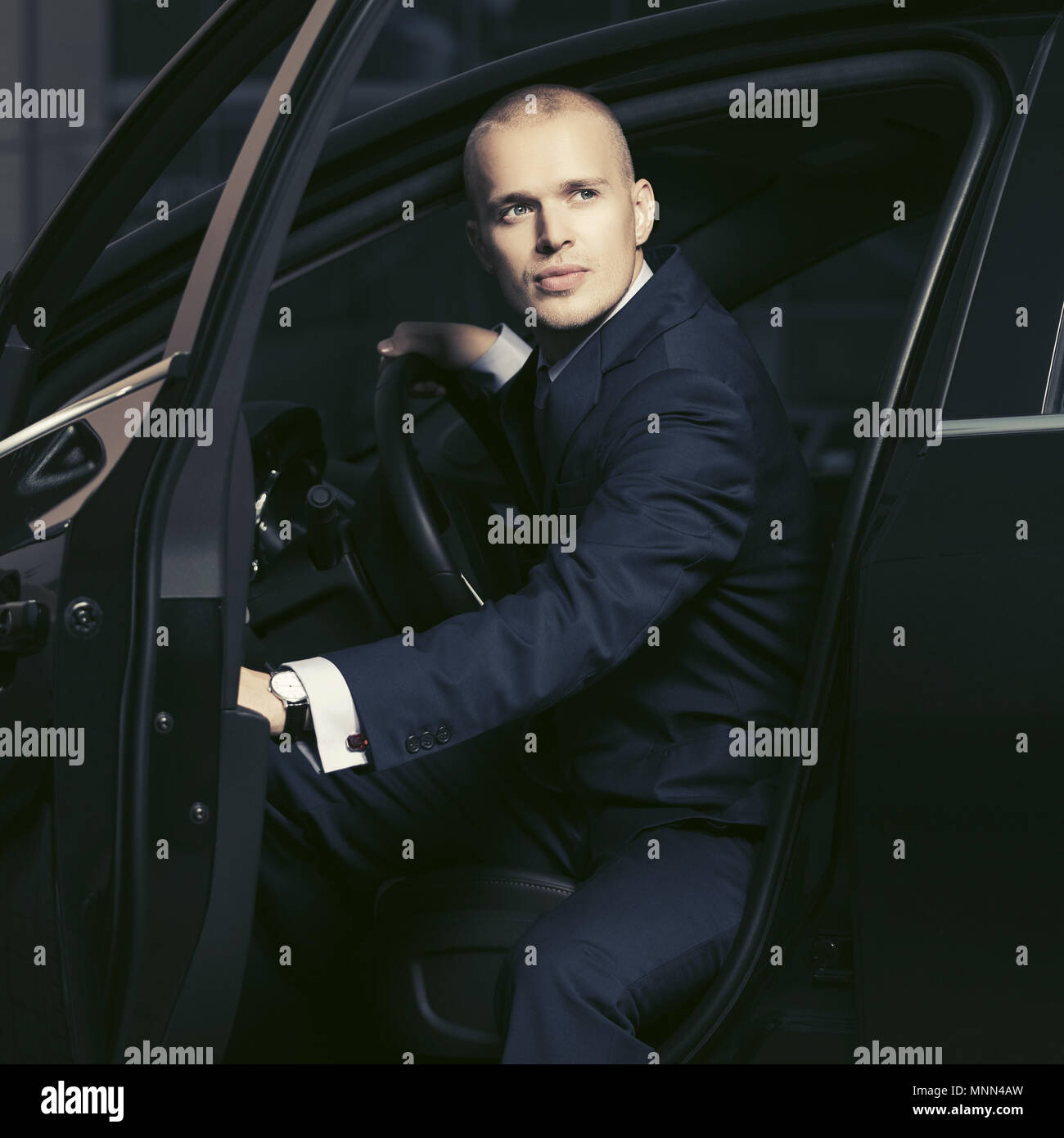 Young handsome businessman wearing costume bleu foncé assise dans une voiture Banque D'Images