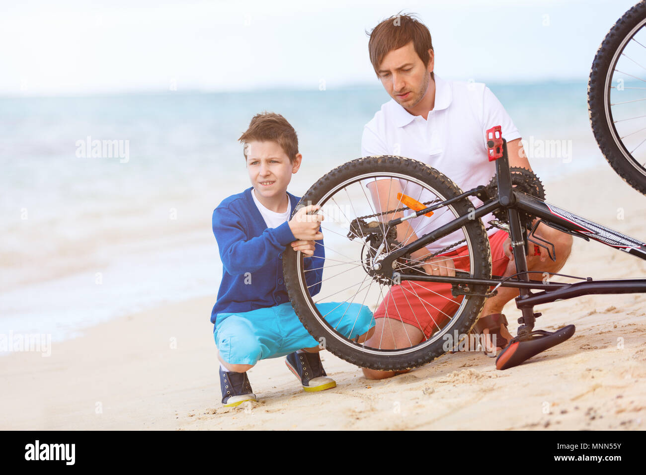 Adolescent et son père la réparation de vélo à l'extérieur à l'été Banque D'Images