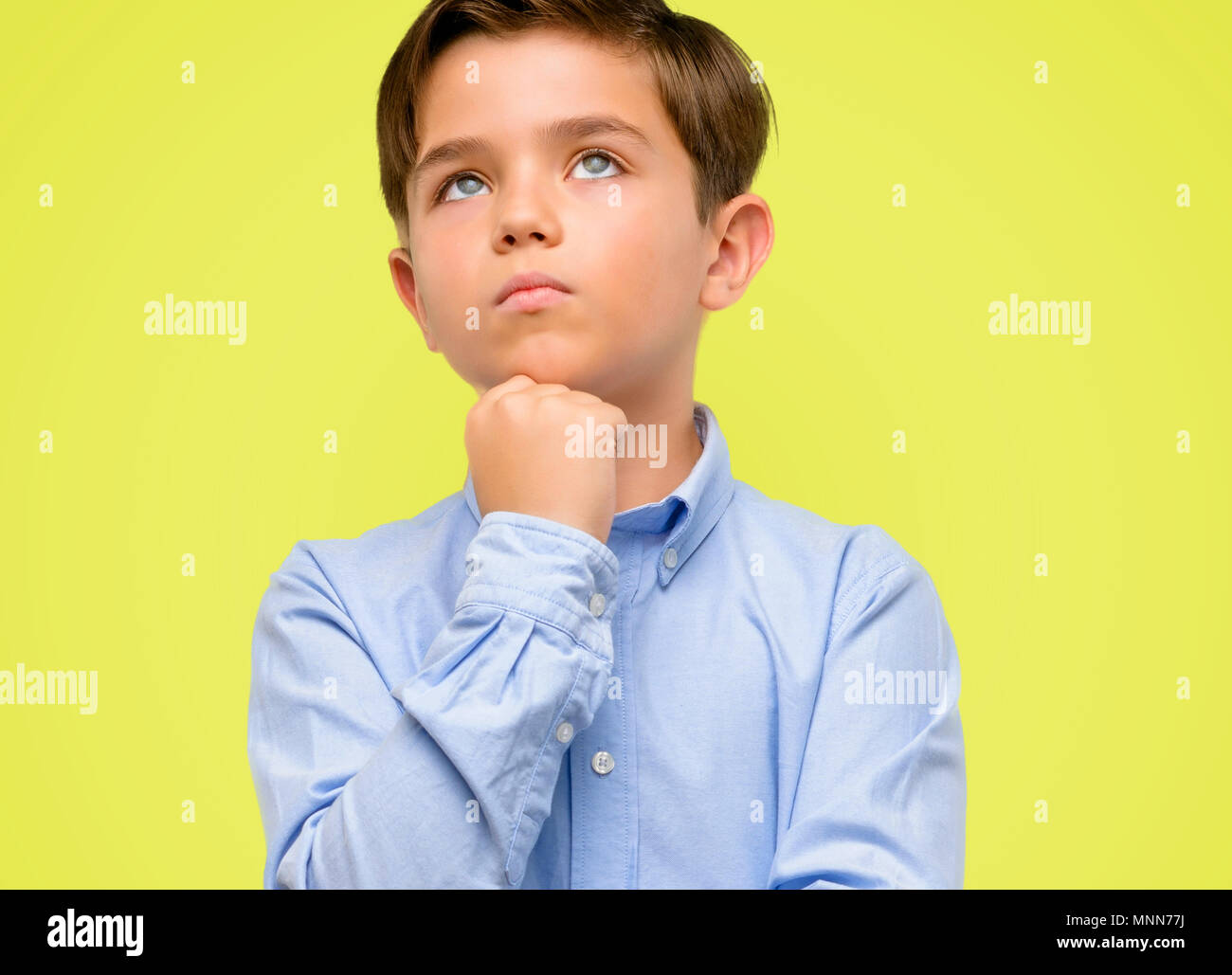Beau Tout Petit Enfant Aux Yeux Verts Jusqu A La Pensee Et L Expression De Doute Et Me Demande Sur Fond Jaune Photo Stock Alamy