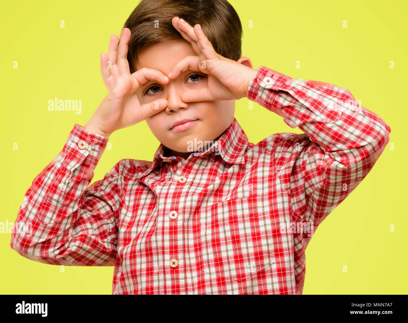 Beau Tout Petit Enfant Aux Yeux Verts A La Camera A L Intermediaire De Doigts En Geste Ok L Imitation Des Jumelles Sur Fond Jaune Photo Stock Alamy