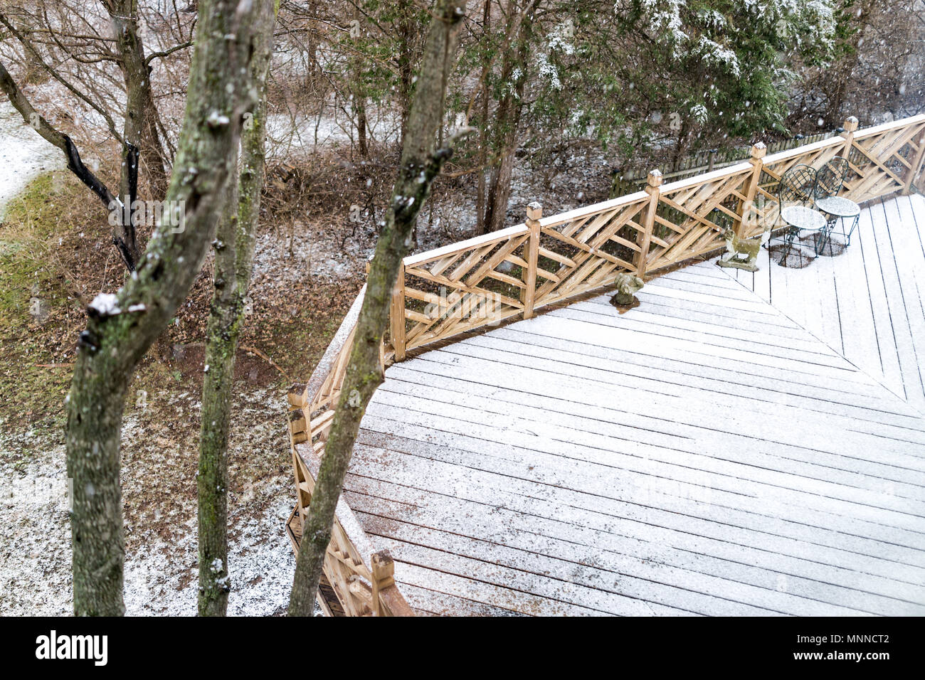 Gros plan du pont en bois vides de la maison avec des chaises, arbres, forêt, décorations sur cour dans quartier avec plancher de bois couvertes de neige au cours de blizzard Banque D'Images