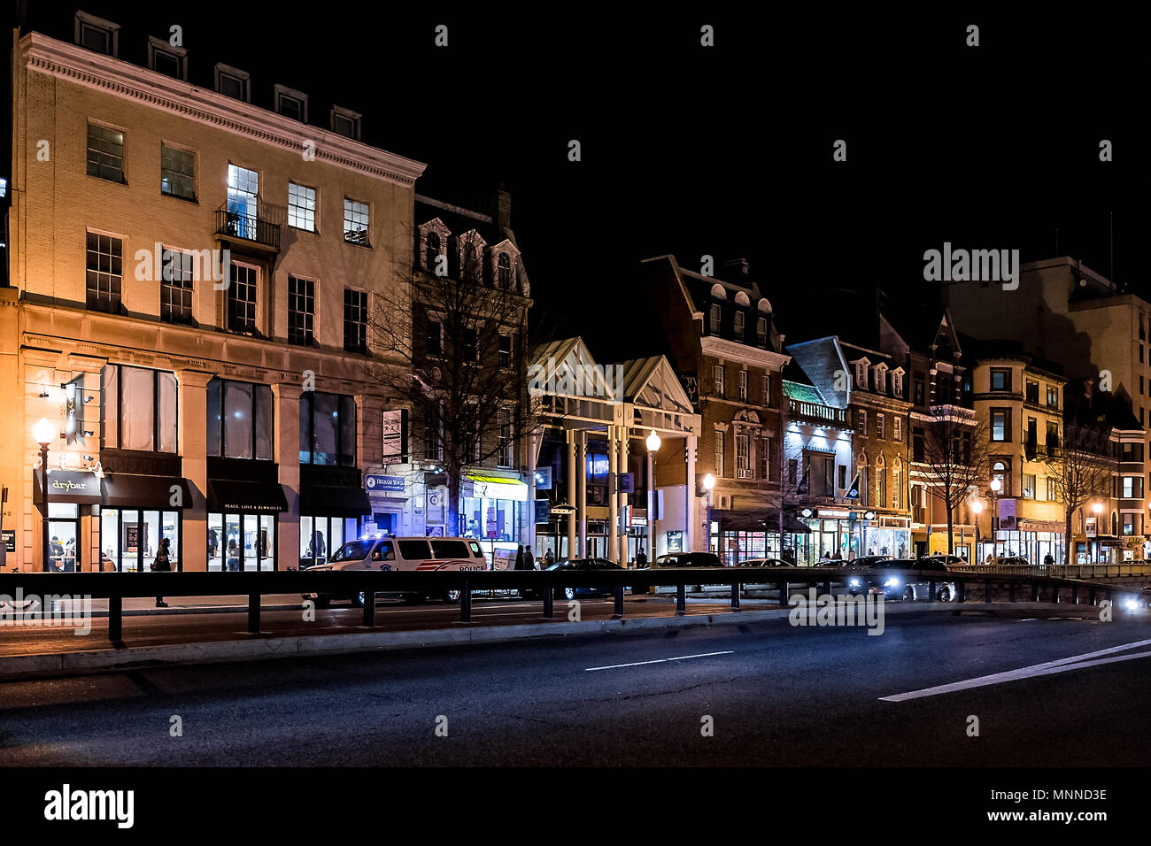 Washington DC, USA - 9 mars, 2018 : Street road dans le quartier de Dupont Circle, avec des magasins, des boutiques et des voitures dans la circulation en soirée d'hiver, éclairé par Banque D'Images