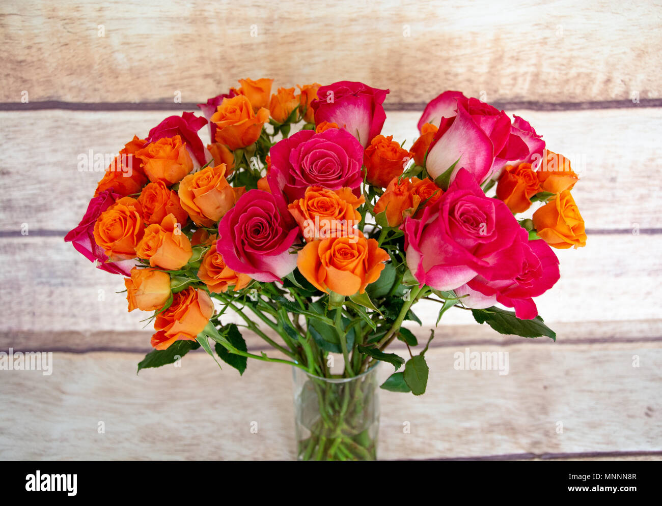Un beau bouquet coloré de blanc avec des bouts roses et des roses orange sur fond de grain de bois. Banque D'Images