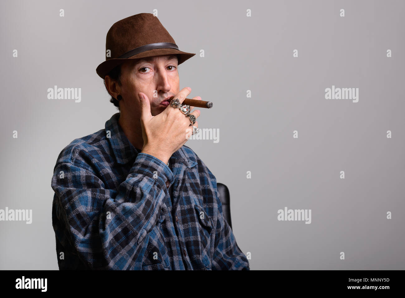 Studio shot of mature gangster man smoking cigar Banque D'Images