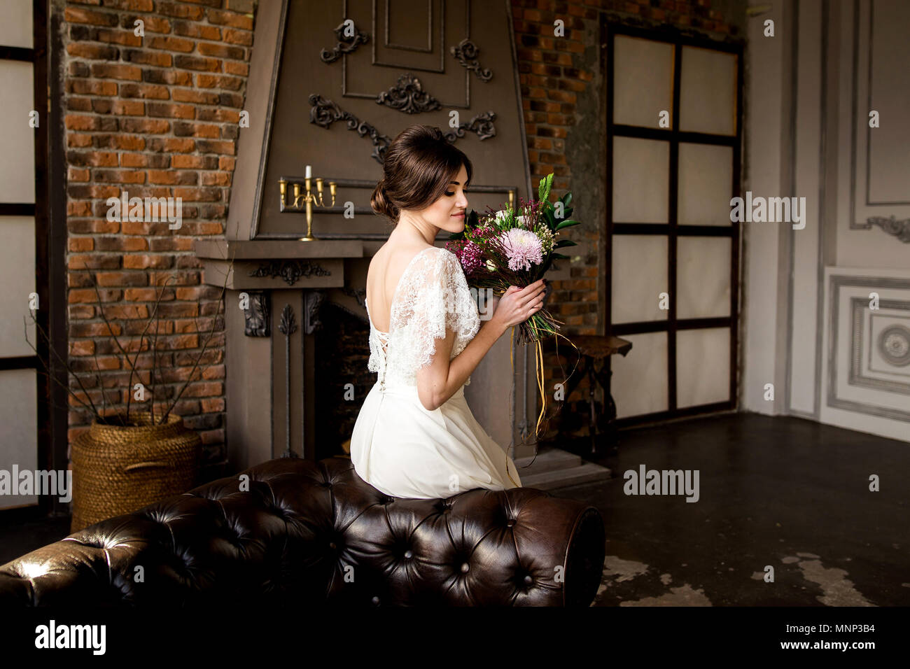 Belle robe de mariée assis sur une chaise à l'intérieur dans dark studio intérieur comme à la maison. Banque D'Images