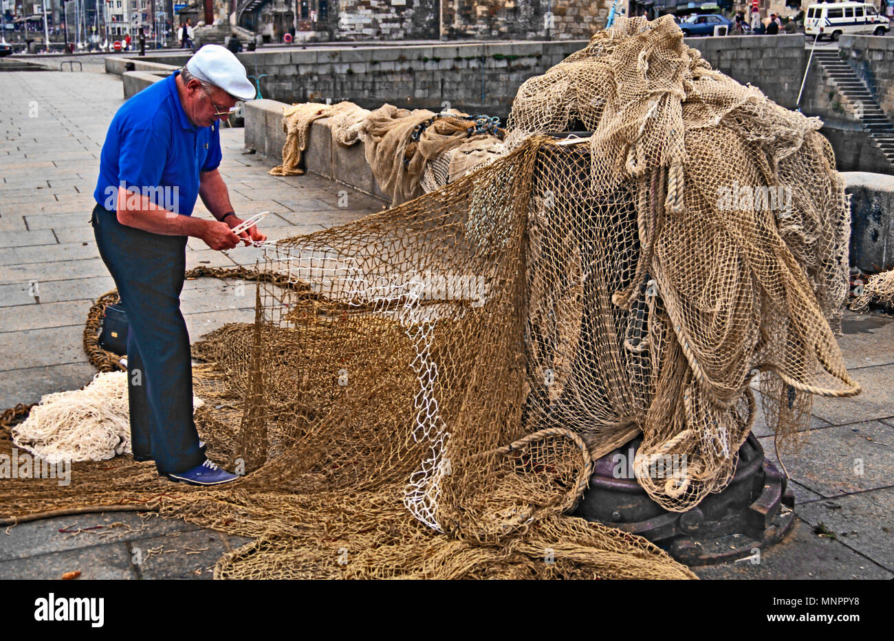 La réparation des filets de pêche pêcheur. HONFLEUR, NORMANDIE, France, juin 2014. Les pêcheurs de réparer ses filets de pêche sur le quai de Honfleur, Norma Banque D'Images