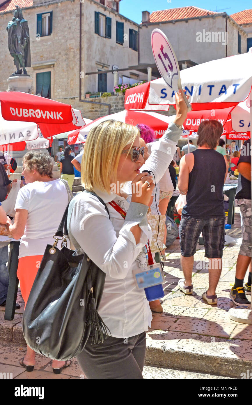 Close up femme tour guide parler d'informations en temps réel dans le microphone liens audio à son groupe de touristes le long de la suite d'écouteurs Dubrovnik visite guidée Banque D'Images