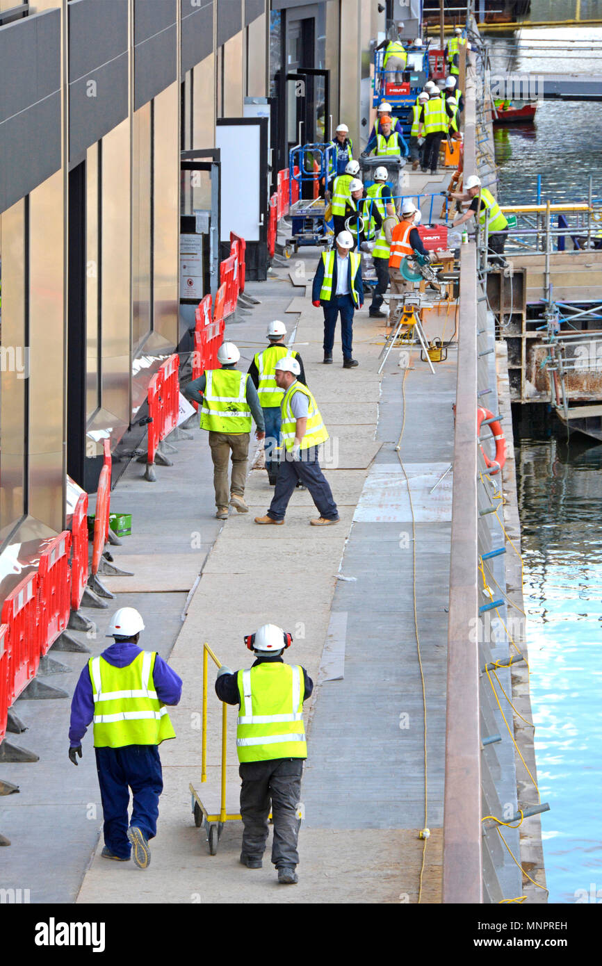 Les travailleurs de l'industrie du bâtiment construction site wearing high viz jacket travaillant sur Canary Wharf de magasins de détail au-dessus de nouveau traverse Elizabeth ligne station UK Banque D'Images