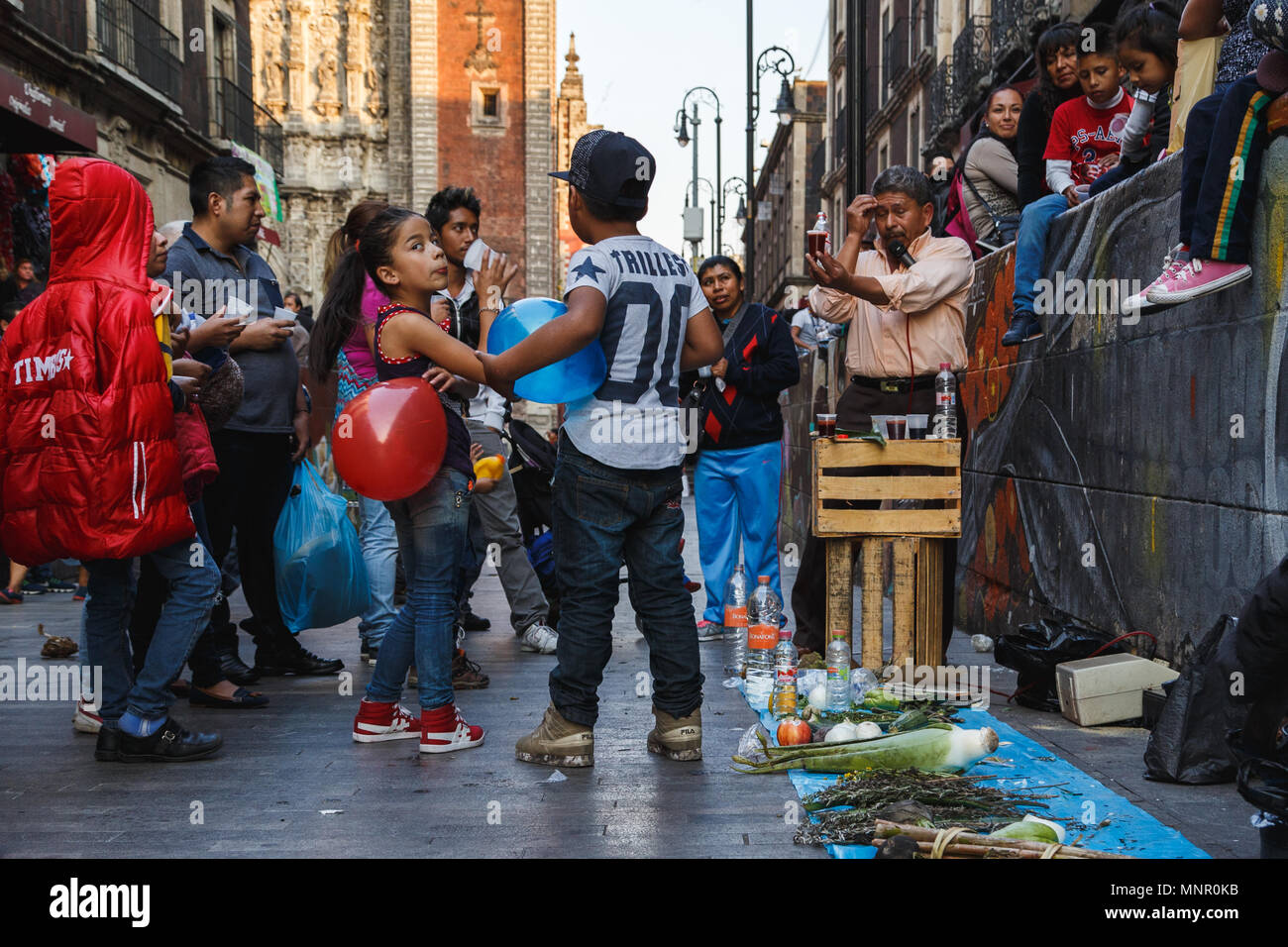 Adultes et enfants se retrouvent autour d'un tonique à base de plantes médicinales traditionnelles des échantillons de dégustation vendeur dans la rue du district central, Mexico, Mexique. Banque D'Images