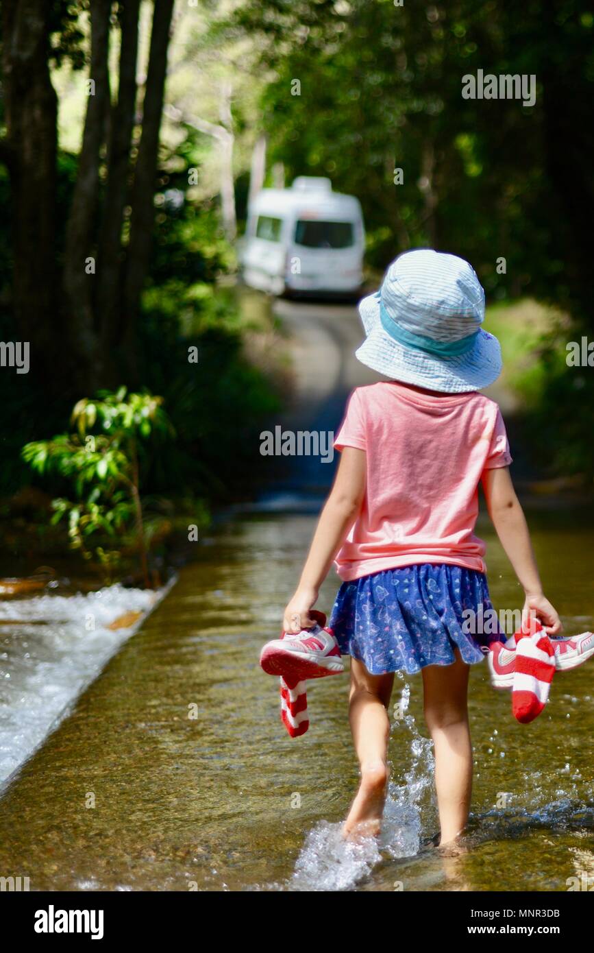 Un enfant traverse la rivière traversant à pied tout en maintenant les chaussures et chaussettes, Jourama Falls, Bruce Hwy, Yuruga France Banque D'Images
