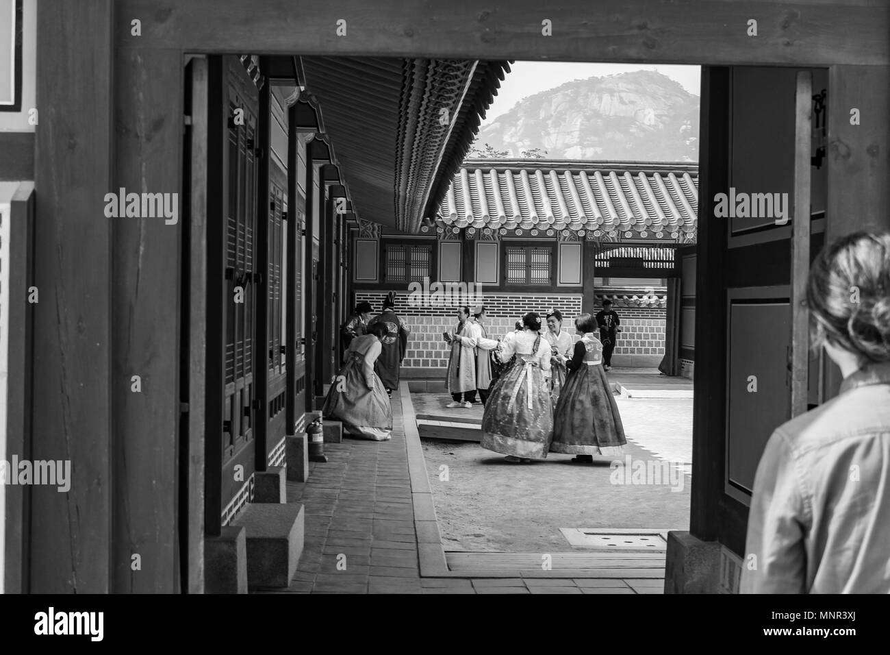 Photo monochrome de regarder dans une cour au Palais Gyeongbokgung, Séoul, Corée du Sud, où les gens sont habillés en Hanbok Banque D'Images