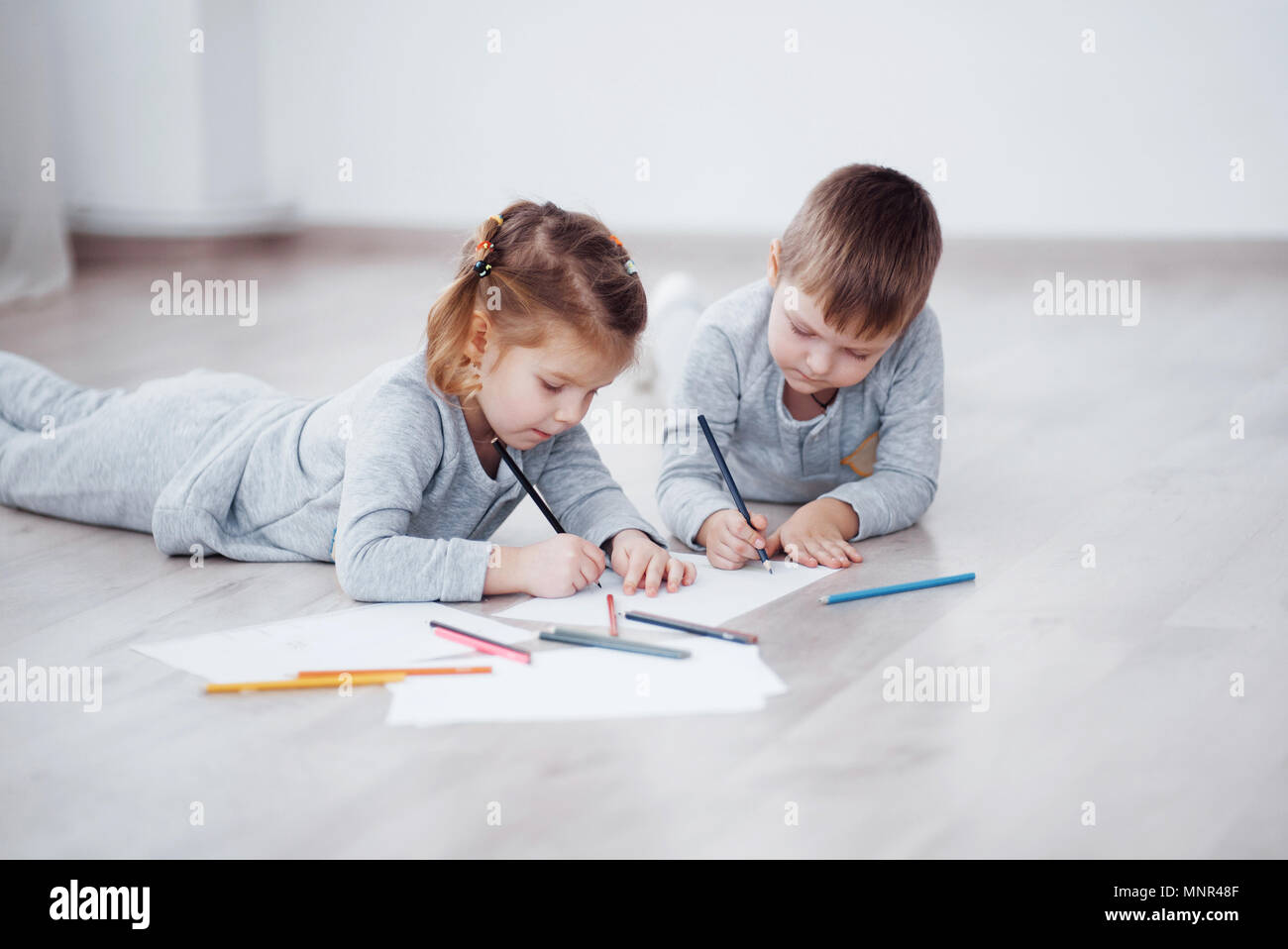 Les enfants se trouvent sur le sol en pyjama et dessiner avec des crayons. Cute child peinture de crayons Banque D'Images