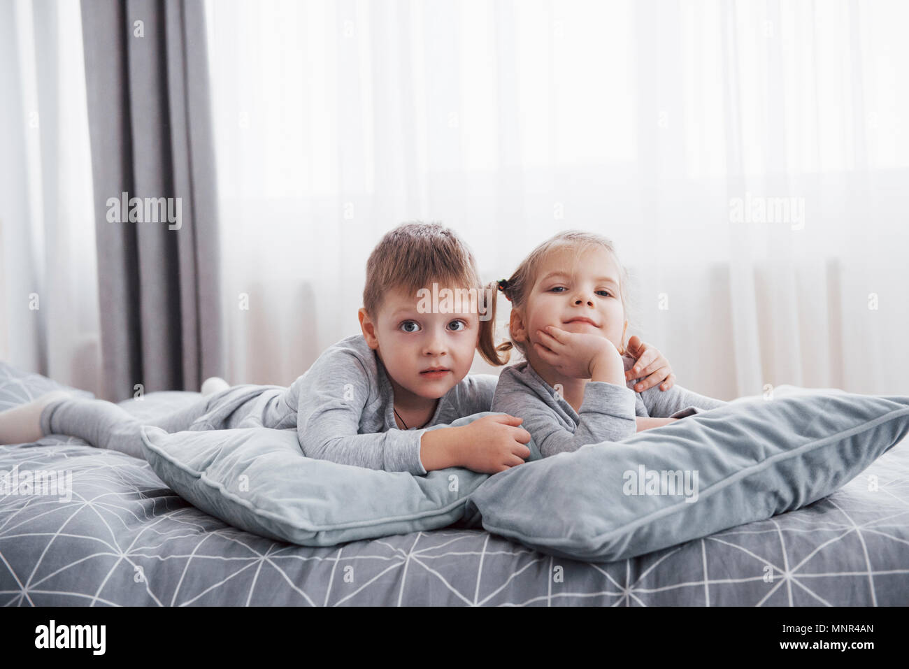 Heureux Les Enfants Jouant Dans La Chambre Blanche Petit Garcon Et Fille Frere Et Sœur Jouer Sur Le Lit Wearing Pajamas L Interieur De Pepiniere Pour Les Enfants Vetements Et Literie Pour Bebe