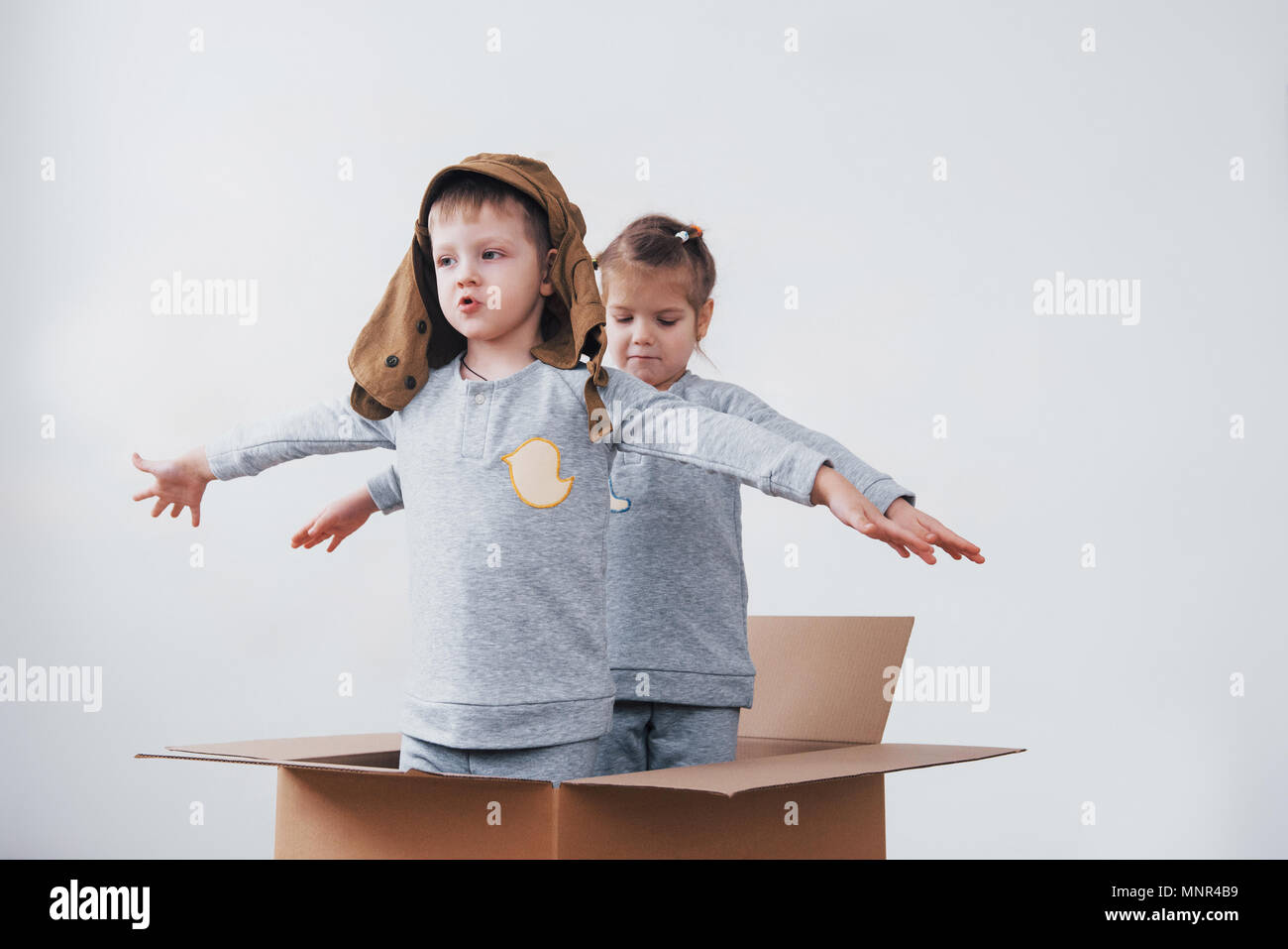 La petite enfance ludique. Petit garçon s'amuser grâce à la boîte de carton. Garçon prétendant être pilote. Little Boy and girl having fun at home Banque D'Images
