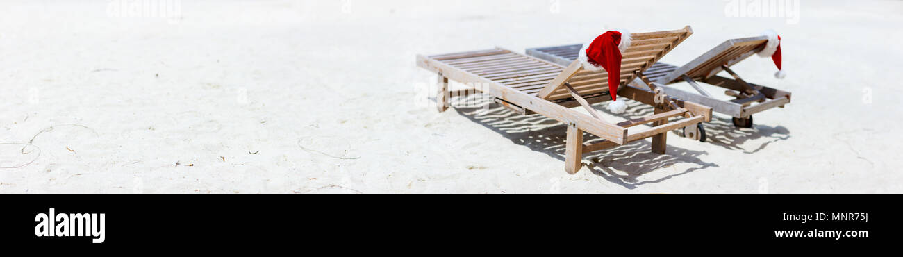 Panorama de deux transats avec Santa hats sur belle plage tropicale avec sable blanc, vacances de Noël parfait Banque D'Images