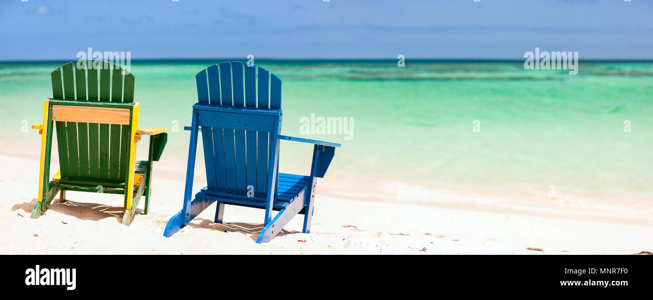 Vert et Bleu Couleur des chaises longues à la plage tropicale dans les Caraïbes avec l'eau de mer turquoise, sable blanc et bleu ciel Banque D'Images