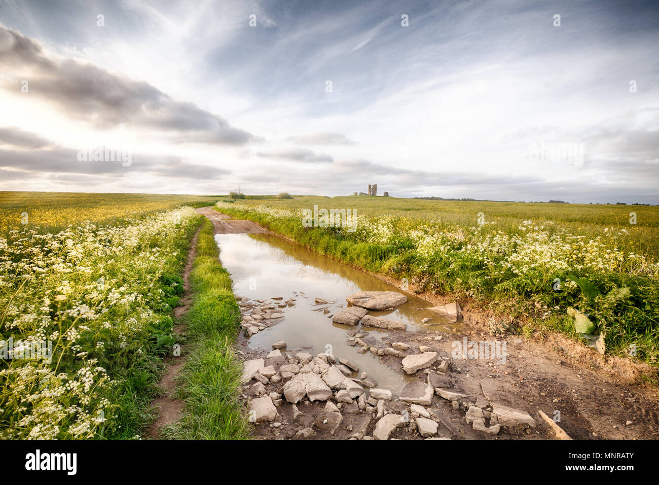 Rocky Road inondées dans un paysage rural menant à une ruine d'une église à Norfolk en Angleterre Banque D'Images