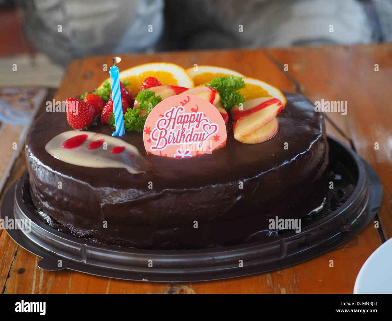 Gateau D Anniversaire Au Chocolat Sur Une Table En Bois Avec Des Fruits Et Une Bougie Allume En Bleu Et Un Happy Birthday Topper Photo Stock Alamy