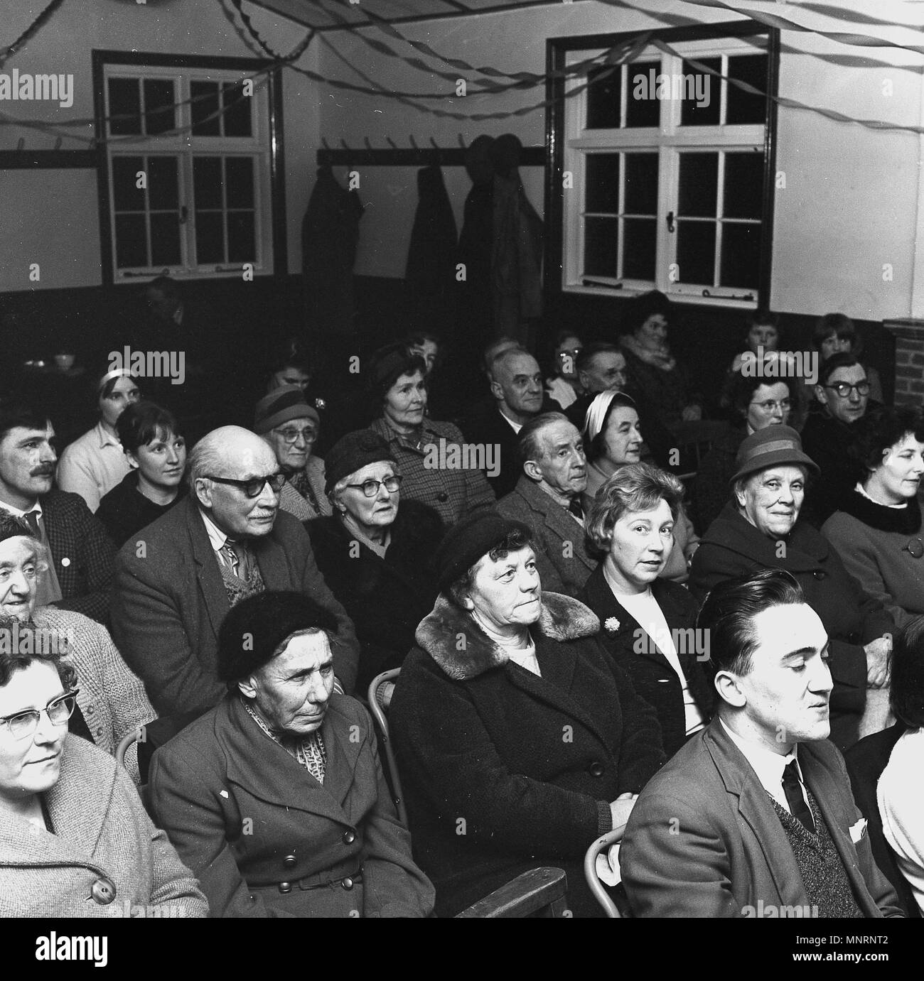 1965, les gens assis à l'intérieur dans une salle des fêtes à l'écoute de concert, England, UK. Banque D'Images