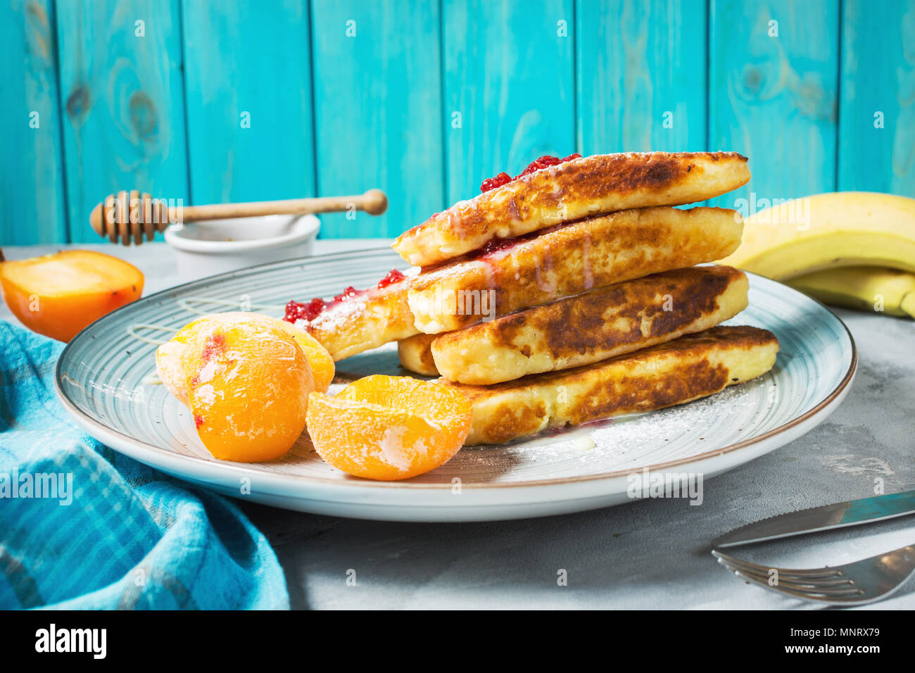 Crêpes de fromage cottage avec l'avoine, syrniki et pêche sur fond de béton. Banque D'Images