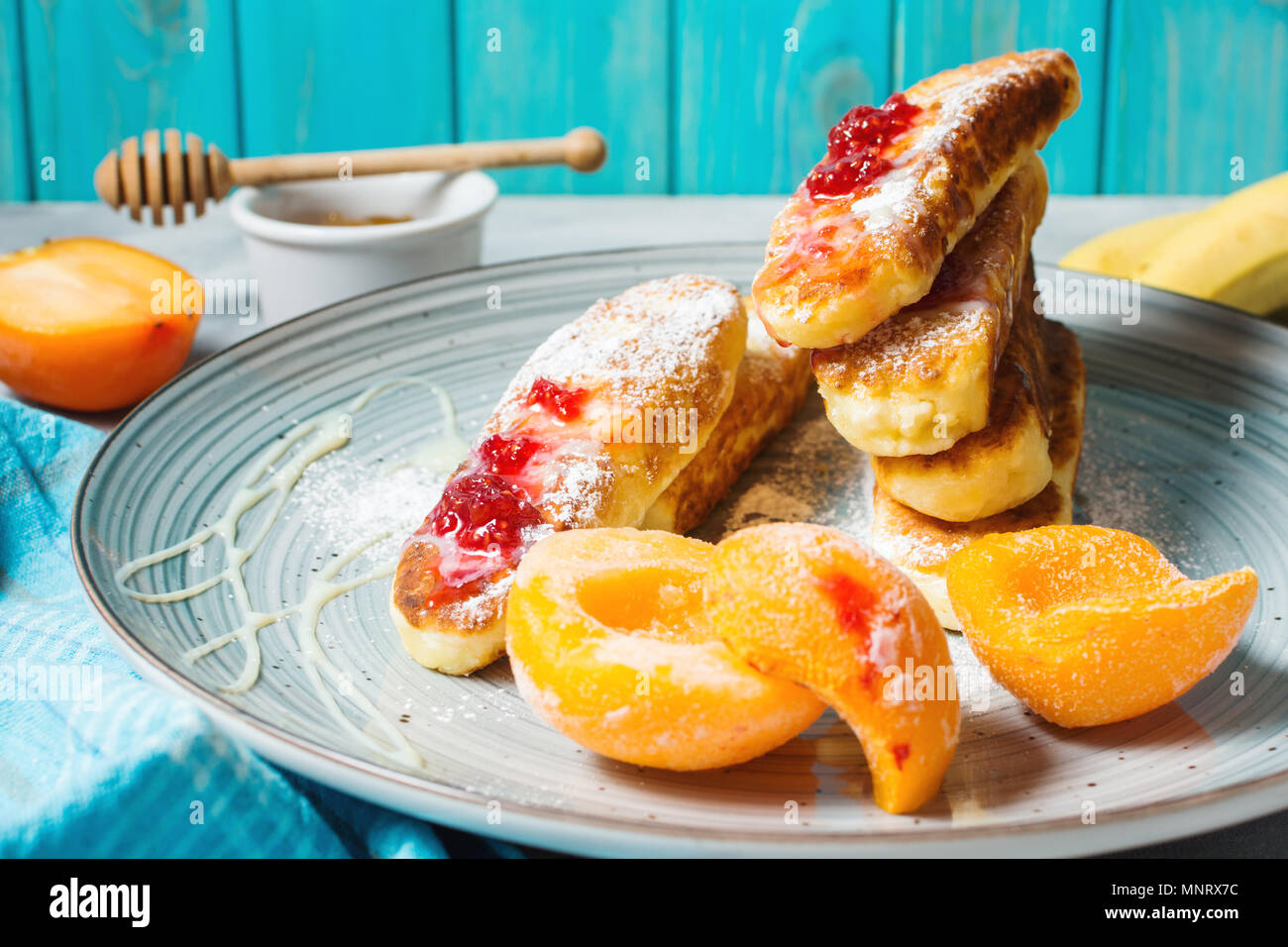 Crêpes de fromage cottage avec l'avoine, syrniki et pêche sur fond de béton. Banque D'Images