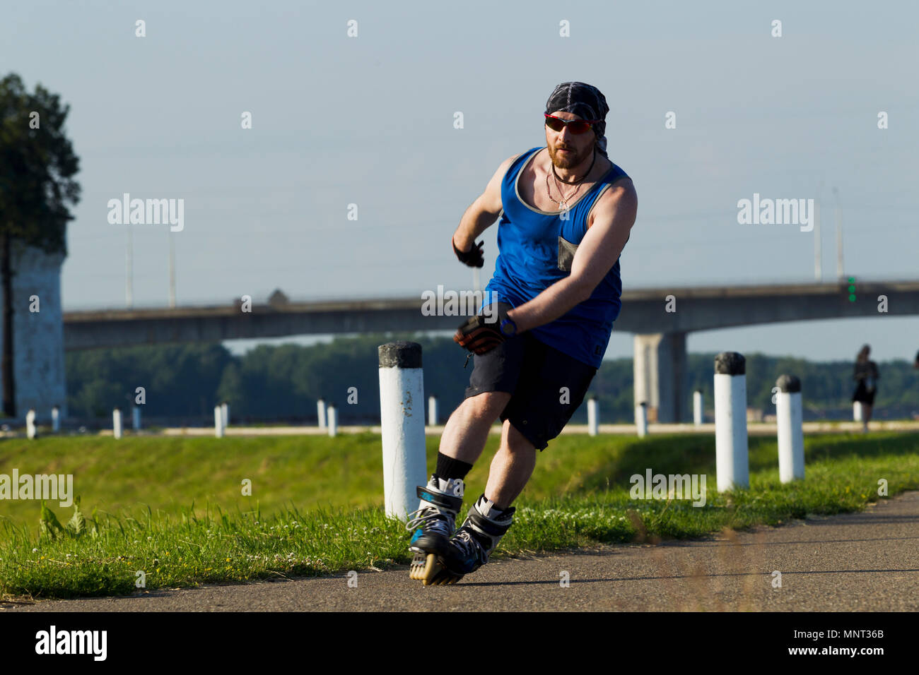 Homme monté sur patins à roulettes dans la ville, éclairées par la lumière naturelle Banque D'Images