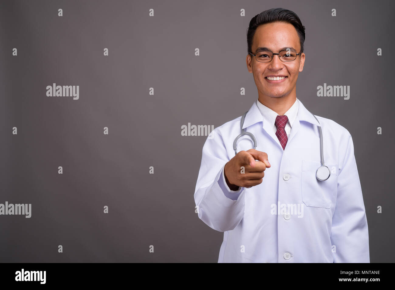 Beau jeune homme indien médecin contre l'arrière-plan gris Banque D'Images
