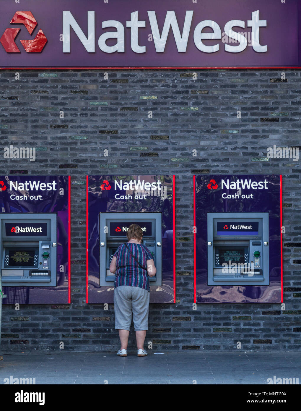 Woman withdrawing cash de Natwest Distributeurs automatiques à Londres Banque D'Images