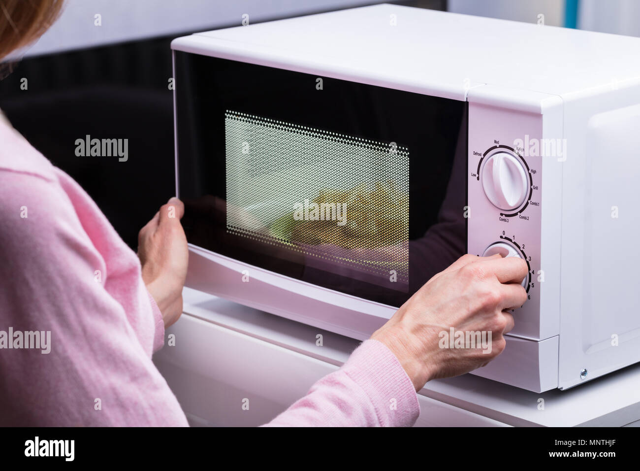 Portrait de femme à l'aide de micro-ondes pour chauffer les aliments à la maison Banque D'Images