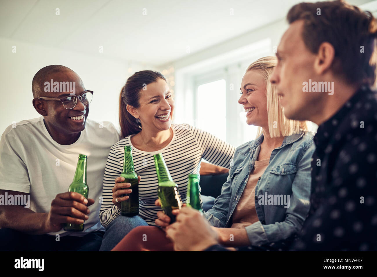 Rire de groupe divers young businesspeople boire des bières tout en détente après le travail dans un bureau moderne Banque D'Images