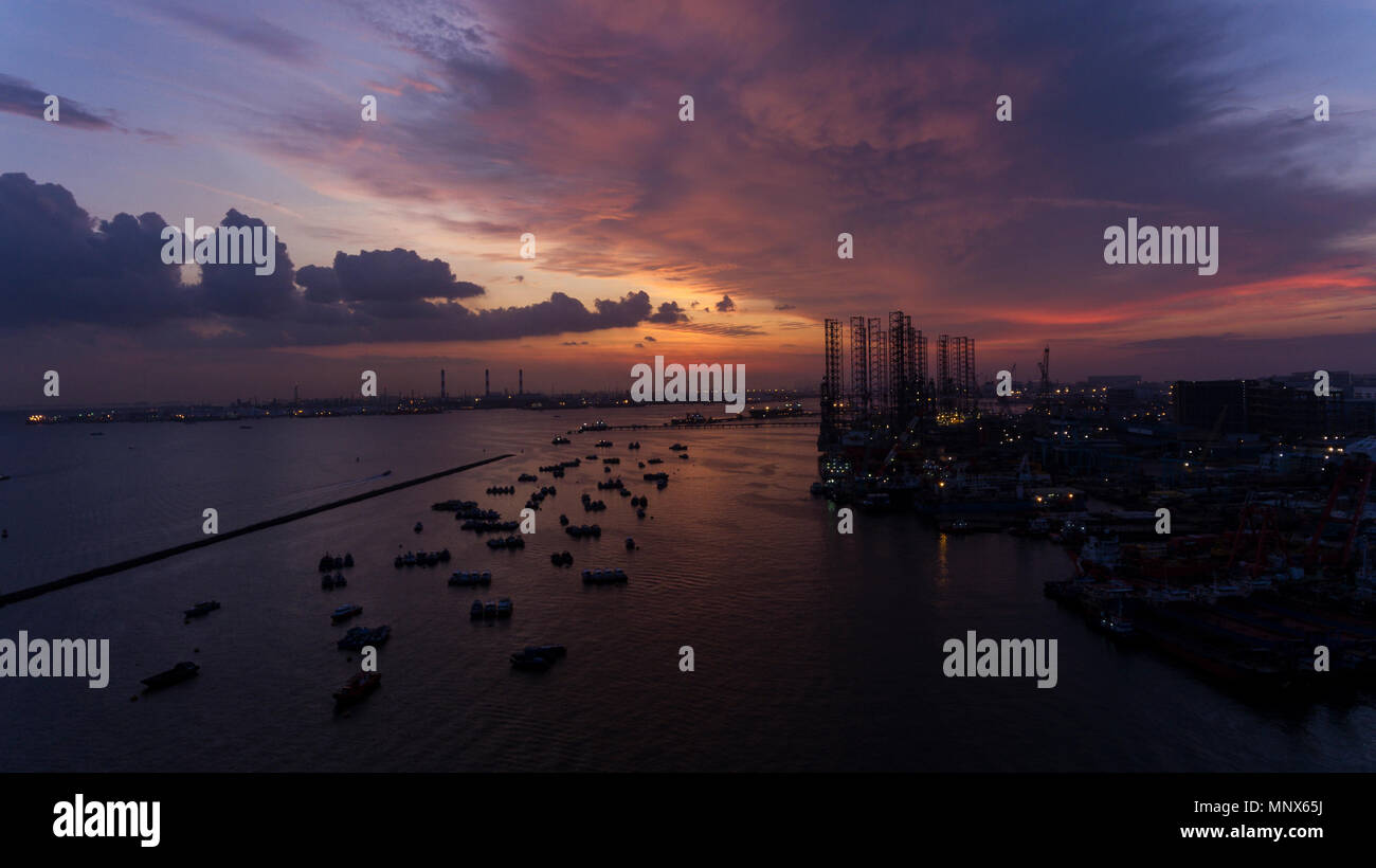 Beau, magnifique coucher de soleil sur l'eau, plus de bateaux dans une zone industrielle à quai ou le port. Ciel nuageux colorées en rouge, orange et jaune par les teintes Banque D'Images