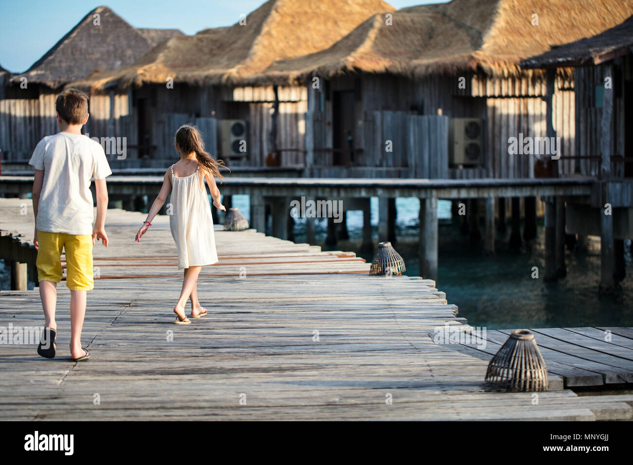 Les jeunes frère et sœur marche sur la passerelle en bois pendant les vacances d'été à luxury resort Banque D'Images