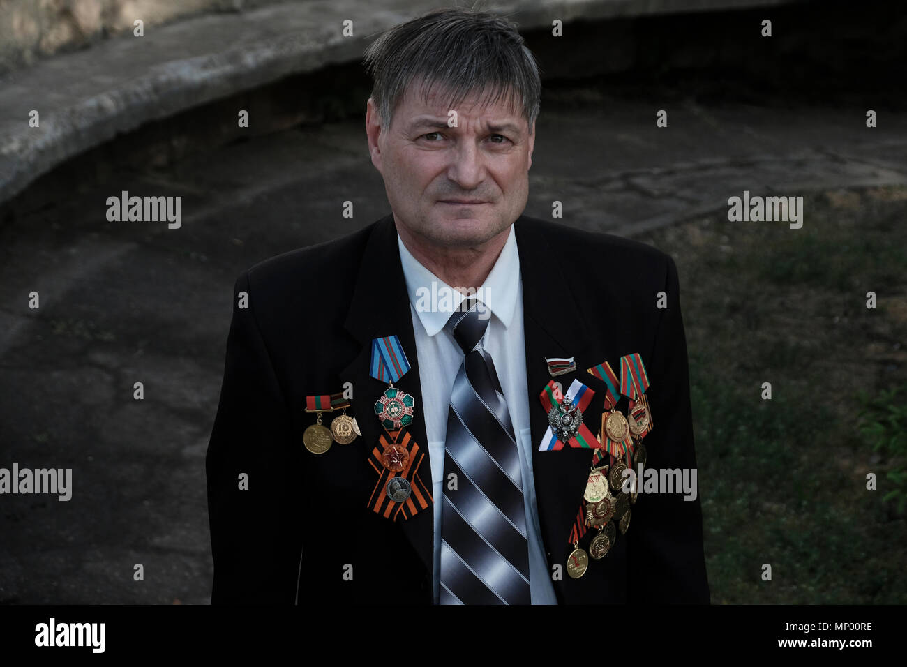 Un vétéran avec des médailles épinglées dans son manteau de costume pose à la caméra lors du jour de la victoire le 9 mai qui commémore la victoire de l'Union soviétique sur l'Allemagne nazie dans le centre de Tiraspol la capitale de Pridnestrovie, officiellement connue sous le nom de République moldave Pridnestrovienne PMR et également appelée Transnistrie depuis 1992 un État sécessionniste enclavé internationalement reconnu comme faisant partie de la Moldavie Banque D'Images