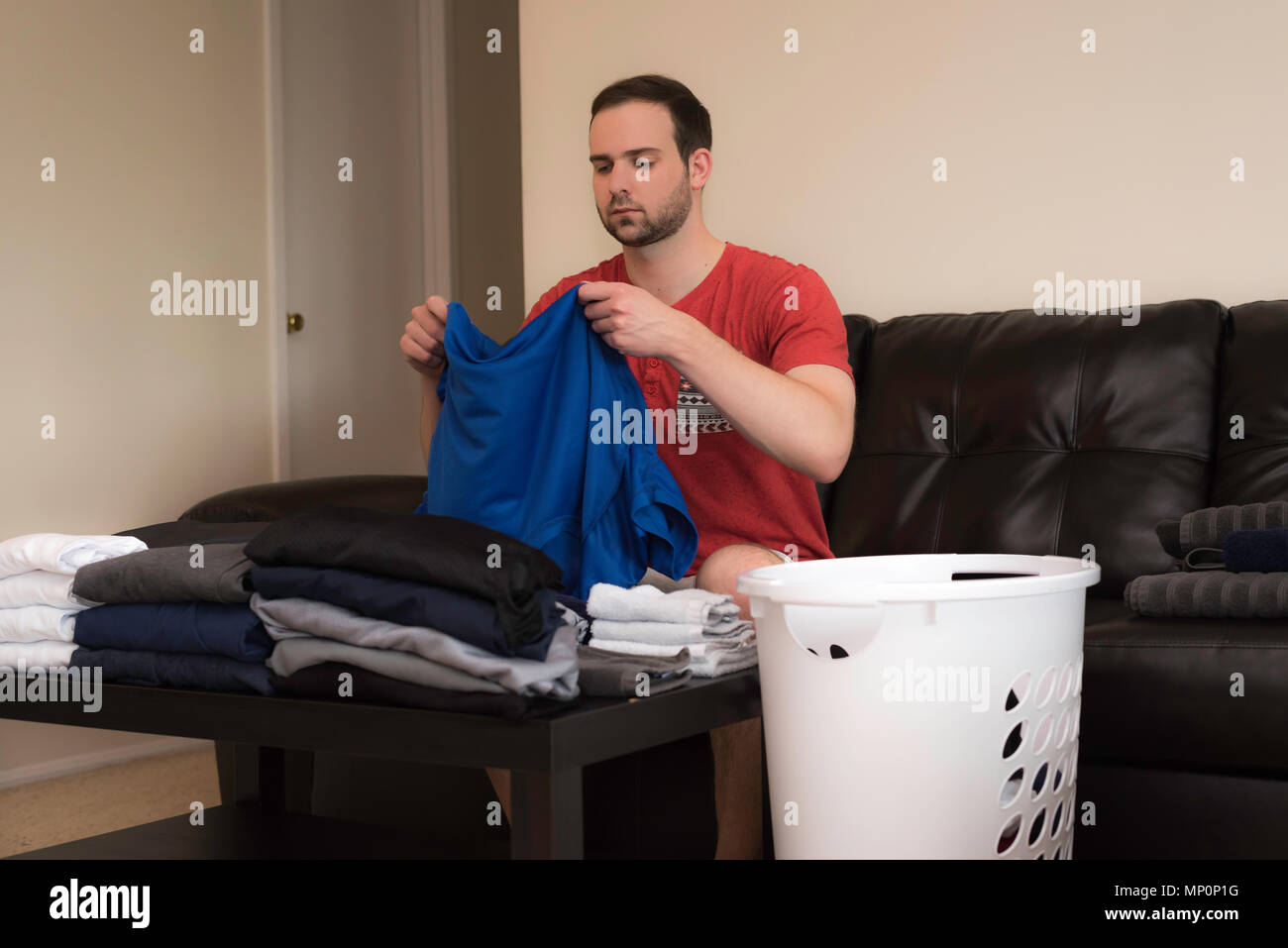 Bel homme folding laundry sur un canapé Banque D'Images