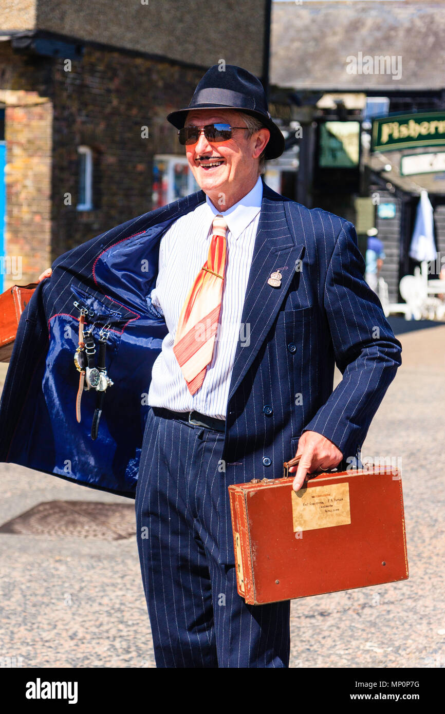 Salut à la 40s populaire événement nostalgique en Angleterre. Middle aged smiling man habillé en veste de guerre spiv tient ouverte pour montrer montres pendaison. Banque D'Images