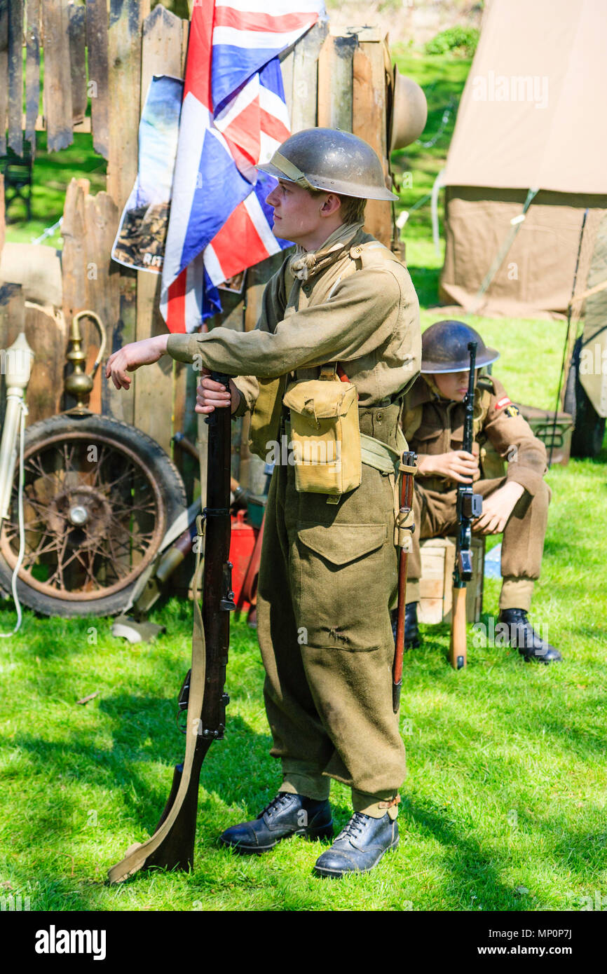 Salut au populaire 40s à l'événement Ville Sandwich, Kent. Jeune homme de la reconstitution médiévale habillé en soldat britannique debout tenant un fusil. Union Jack derrière. Banque D'Images