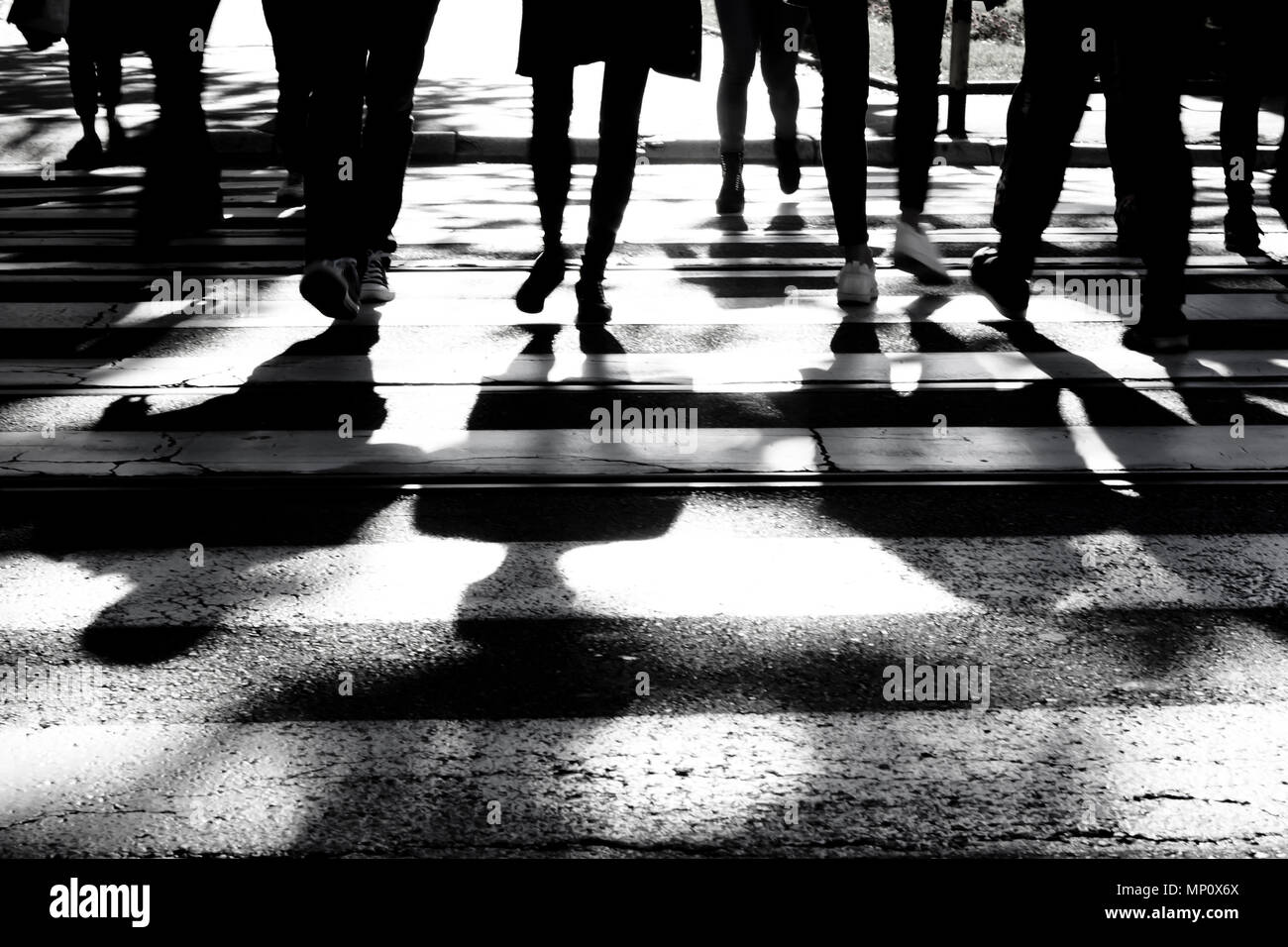 Silhouettes floues et les ombres de personnes traversant la rue sur passage pour piétons en noir et blanc, seules les jambes , méconnaissable Banque D'Images