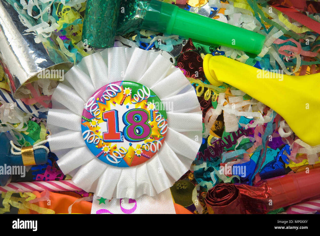 Gros plan d'un 18e anniversaire Rosette Ruban entouré de décorations de fête Banque D'Images