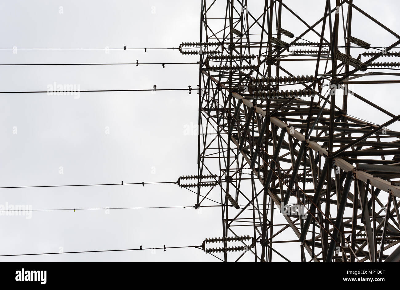 Jusqu'à sur une grande tour de transmission électriques métalliques avec isolateurs parallèle et fils contre ciel couvert. Banque D'Images