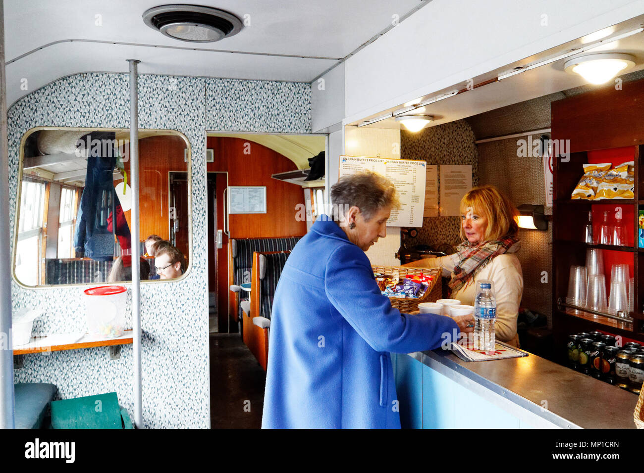 Une femme plus âgée l'achat de thés de la voiture-restaurant sur le pic de fer vapeur Rail, Bakewell, Derbyshire, Angleterre Banque D'Images